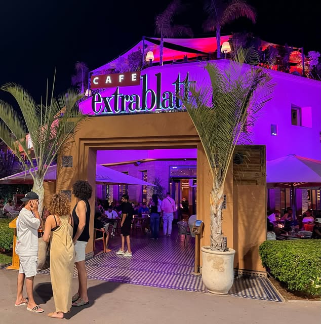 La façade du Café Extrablatt illuminée en violet la nuit