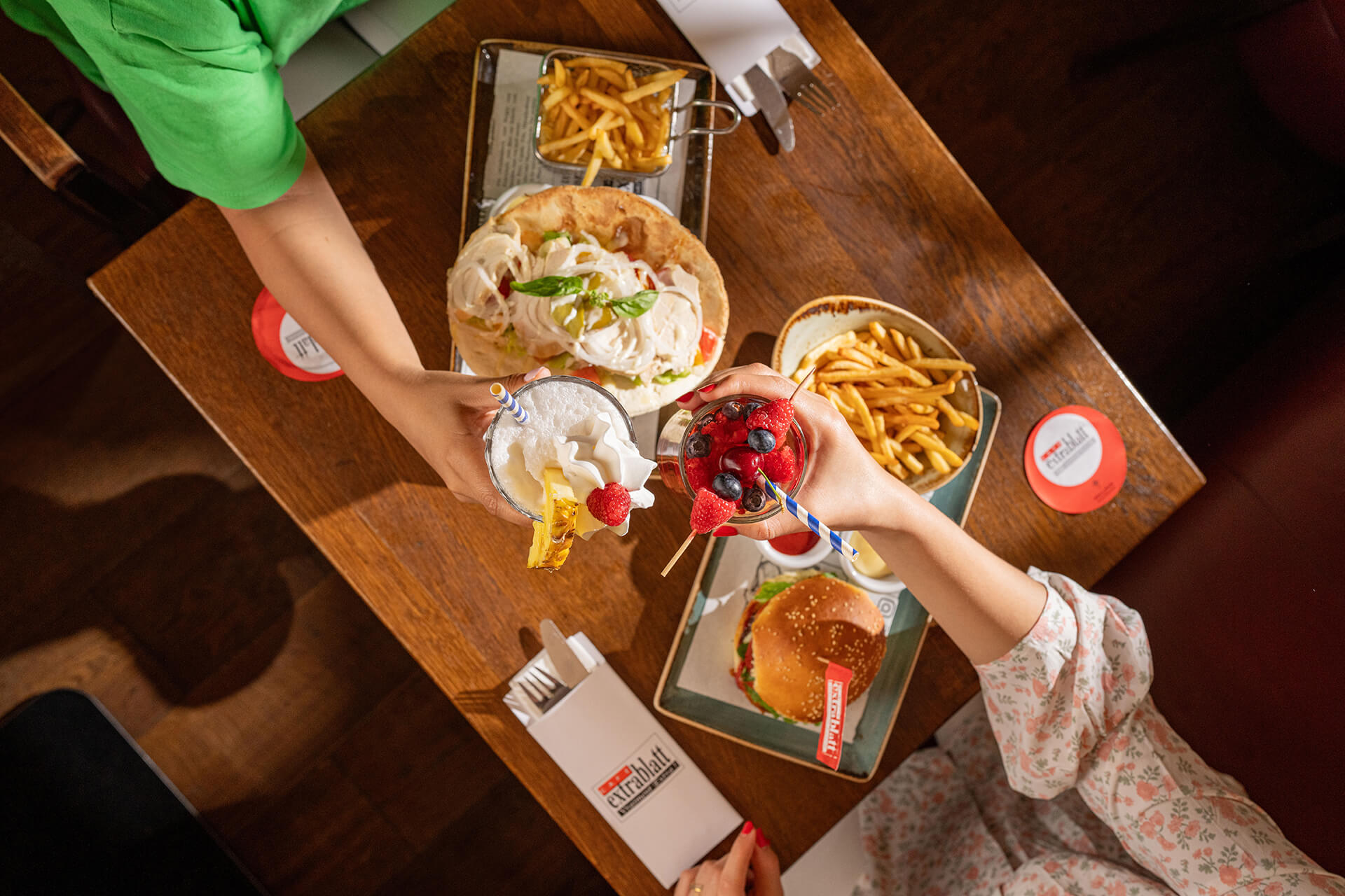 Vue de dessus d'une table : pita, burger, frites, milkshake et cocktail